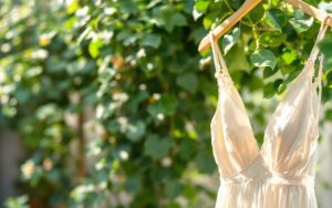 une-robe-dete-elegante-accrochee-a-un-support-en-bois-avec-une-lumiere-naturelle-douce-et-un-fond-de-verdure-luxuriante