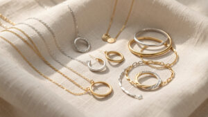 Composition élégante de colliers, créoles, bracelets et anneaux dorés et argentés disposés sur un tissu clair.