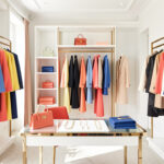 Dressing féminin lumineux présentant des vêtements coordonnés, des accessoires sobres et des touches colorées dans une mise en scène éditoriale élégante.